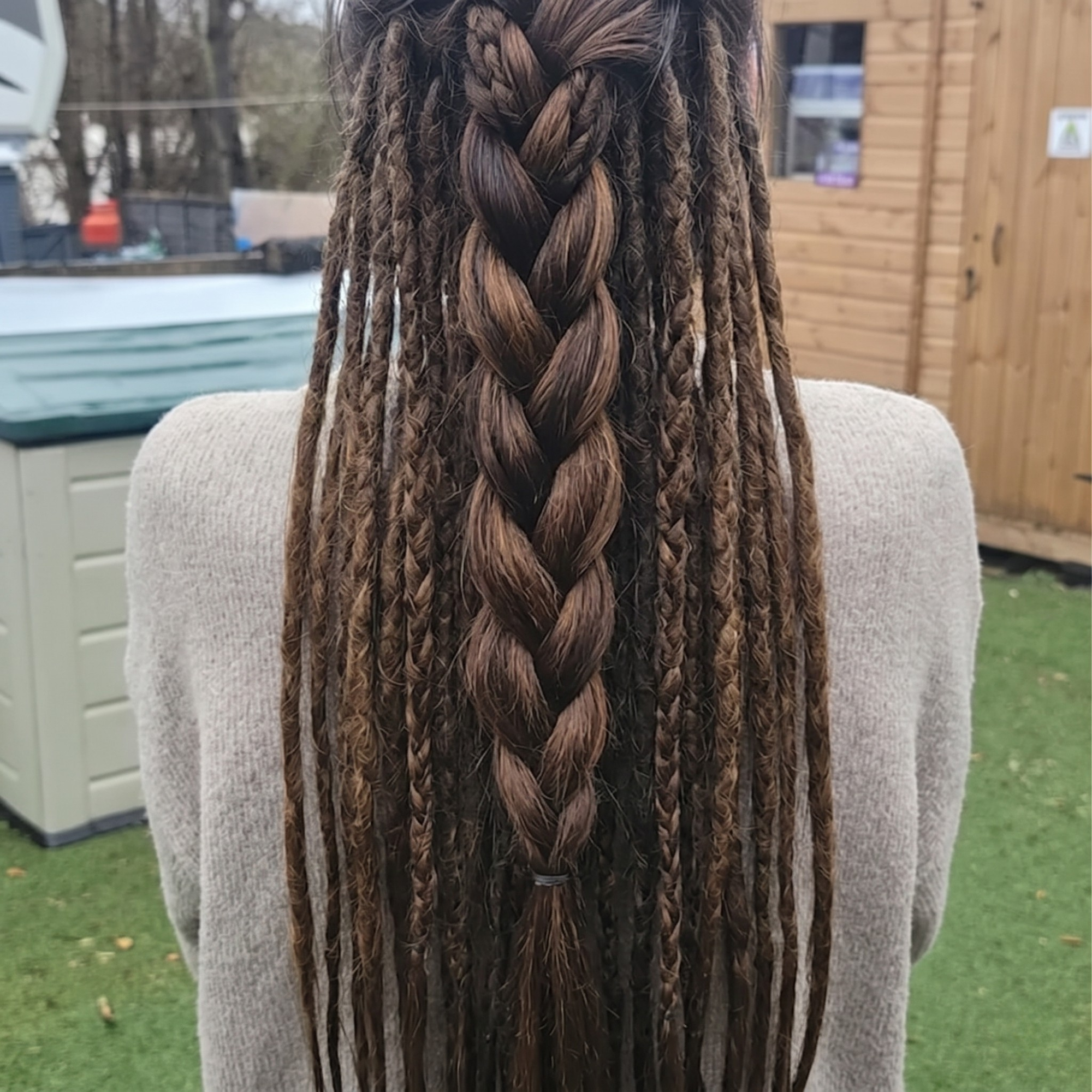 Back view of boho brown dreadlock extensions installed with braided styling, mixed textures and natural loose ends.
