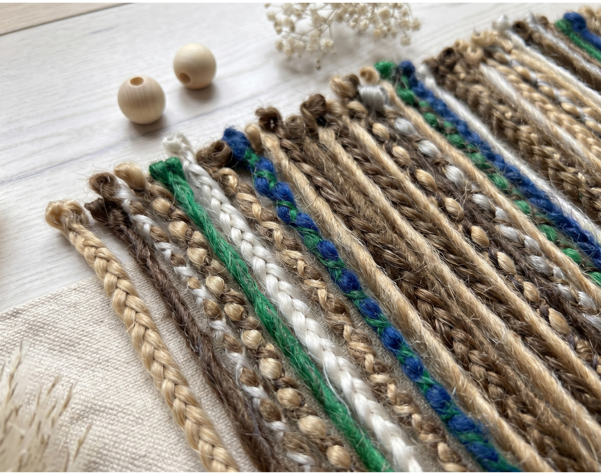 Close-up of synthetic dreadlock extensions showing braided texture, loose ends, and mixed blonde, brown, blue, green and white colours.